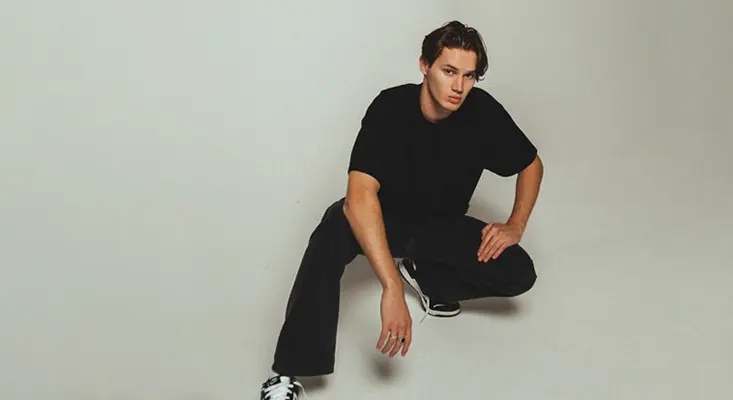 Dutch DJ Mau P in an all-black outfit, kneeling for a photo shoot promoting his track "Like I Like It