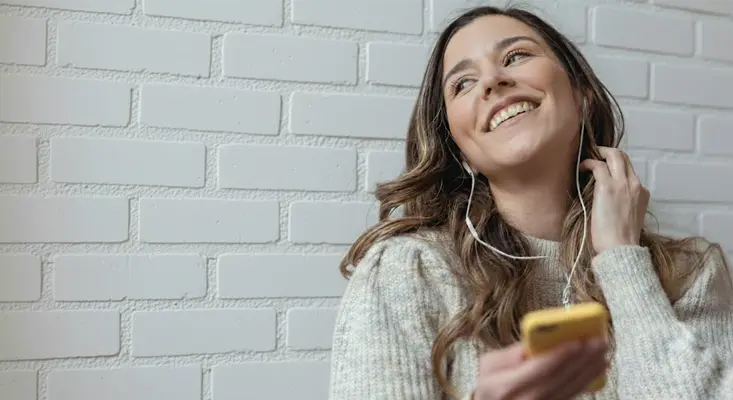 Woman smiling while listening to music through wired headphones.