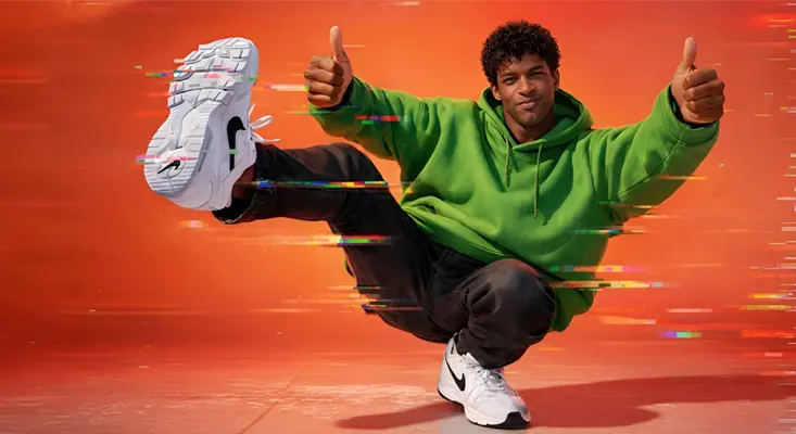 A Hip-Hop dancer performing a power move against a vibrant orange background with digital glitch effects, representing Glitch Hop music.