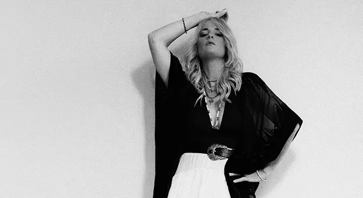 Singer Elles Bailey posing in a black kimono and white skirt for an album interview.