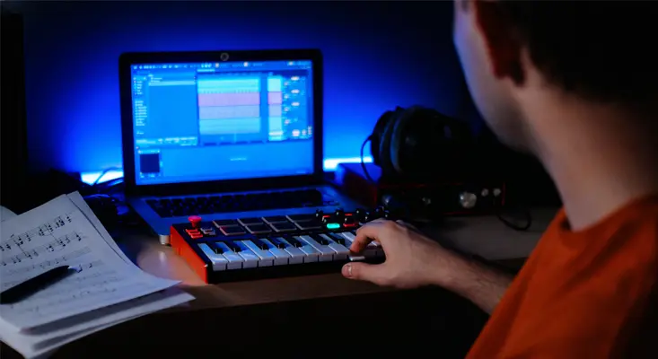 A music producer using the LANDR music platform for AI-driven mastering, distribution, and creative tools in a modern home studio.
