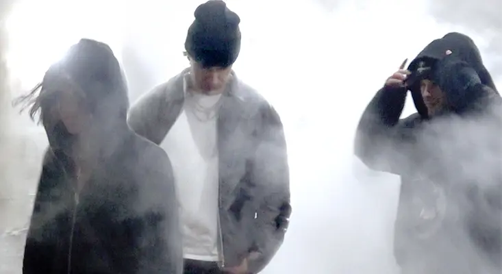 Three members of LE YORA standing in heavy white smoke, dressed in hooded jackets and a beanie — via Alta Music Group.