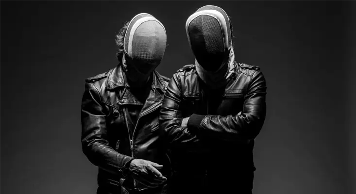 Craving Dark Synthpop? “Different” By BLACKBOOK Is Your Fix BLACKBOOK synthpop duo wearing fencing masks and leather jackets in a dramatic black and white photo.