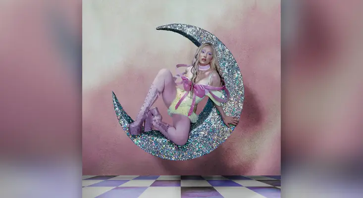 LUNA sitting on a large glittery crescent moon in the Heavenly cover art, featuring pink and yellow high-fashion attire on a checkered floor.