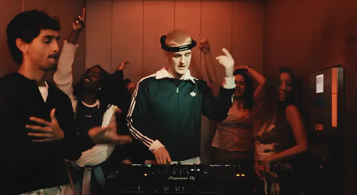 BL3SS DJing an elevator party surrounded by dancers in his terms and conditions music video.