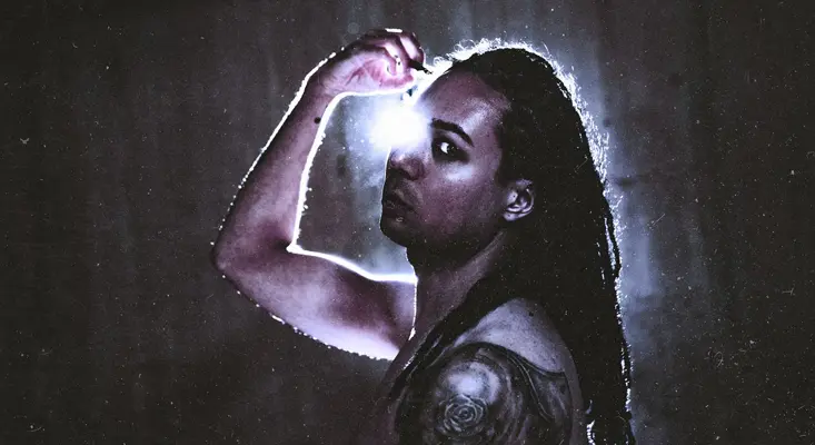 Goth Band Hurtsfall Challenges Mortality In “Memento Mori” Lead singer Sam Harrison Emm of Goth band Hurtsfall with dark makeup and long dreadlocks holding a bright light to his eye, representing the themes of Memento Mori and mortality.