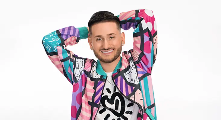 Kory Burns smiling in a colorful jacket for his new single The Dizney Song.