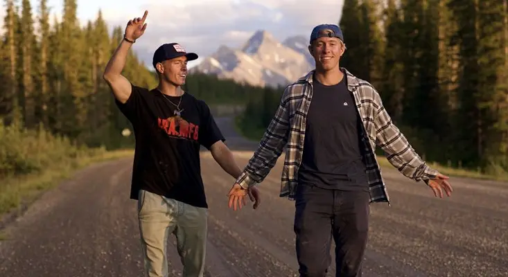 MC4D twin DJs Matt and Chris Drake walking on a mountain road surrounded by trees and peaks during their COMPASS album campaign.