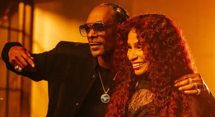 Chaka Khan Brings Fresh Disco Music With Snoop Dogg Chaka Khan and Snoop Dogg smiling together on the music video set for Boogie's in My Soul under warm amber lighting.