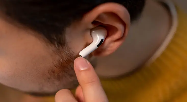 A trusted listener reviews a new track and provides feedback before its streaming release. Listener testing a new song with earbuds before an indie artist streaming debut.