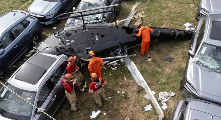 Aerial view of the tragic 2026 Rio de Janeiro mid-air helicopter crash site where Oliver Tree died, showing emergency military firefighters inspecting the wreckage in a car parking lot.