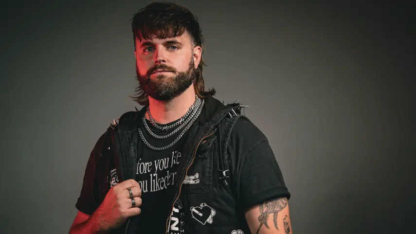 Micah Martin Teases Debut Album ‘All I Need,’ Shares Lead Single Press photo of Micah Martin posing in a studded vest for his debut album All I Need.
