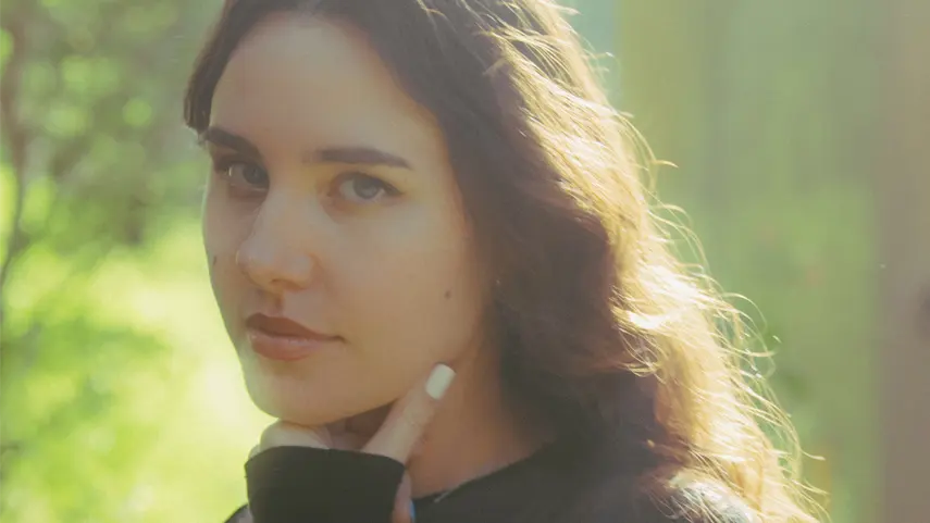 Pretty Girl Is Back After 1 Year With New EP 'Body Step' Close-up portrait of electronic music producer Pretty Girl looking at the camera with a soft sun flare background, promoting her Body Step EP.