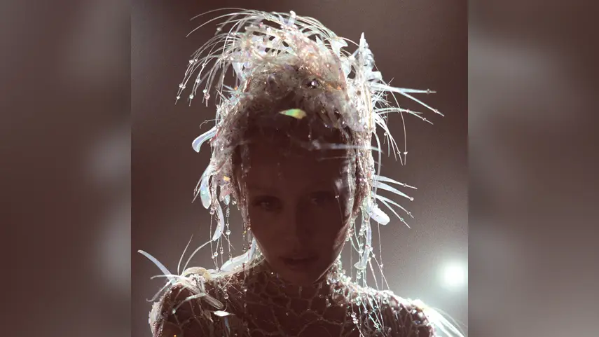 Miley Cyrus wearing an avant garde crystal headpiece on the album cover for Something Beautiful.