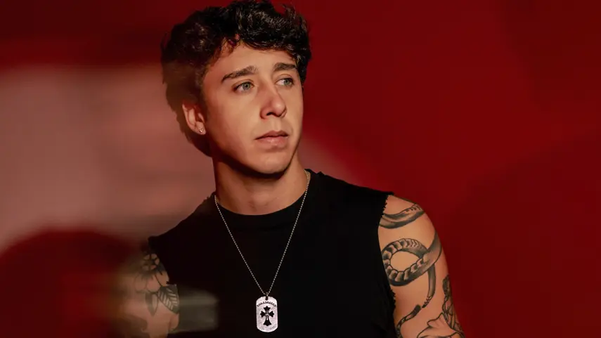ZUEZEU Drops “WEIGHTLESS” With Music Video Shot In Hawaii ZUEZEU wearing a black tank top and dog tag necklace against a red backdrop, promoting his single "WEIGHTLESS."