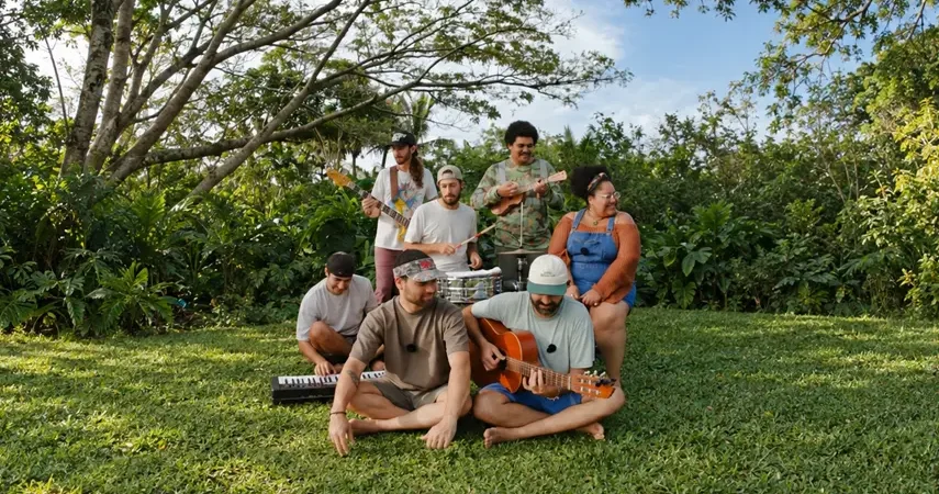 ANYKINE band members playing guitars, drums and keyboard on the grass in a lush tropical garden for the Inertia remix.