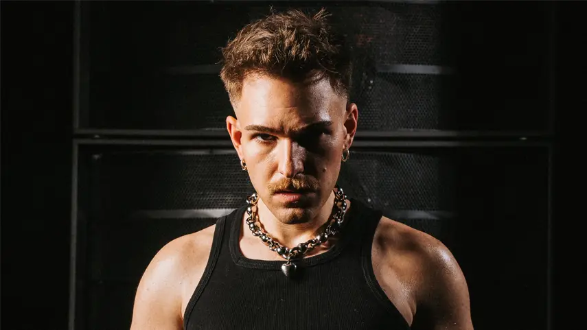 Ely Oaks Reworks Eamon's Hit “F_ck It (I don't want you back)” Ely Oaks wearing a black tank top and layered chain necklace against a dark backdrop, promotional image for his new single F_ck It.