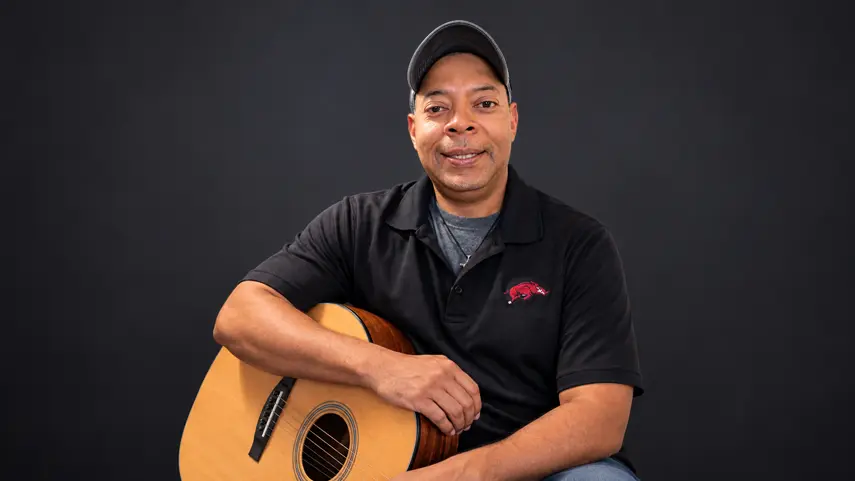 Producer/Songwriter ErickOscar On Music, Process And Identity ErickOscar, producer and songwriter, holding his acoustic guitar during an interview portrait.