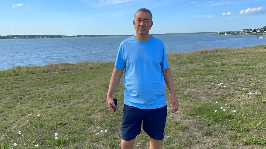 A shot from the official music video for "Hearts Across The Ocean." Gary Louca stands by the water in a still from the Hearts Across The Ocean music video.