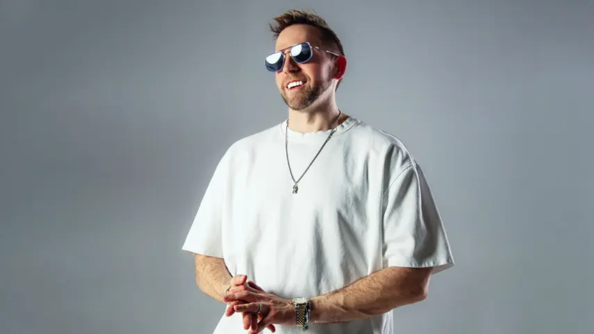 Underground Techno DJ Sam WOLFE Shoots Video In Atlanta Underground techno DJ Sam Wolfe smiling in white t-shirt and sunglasses.
