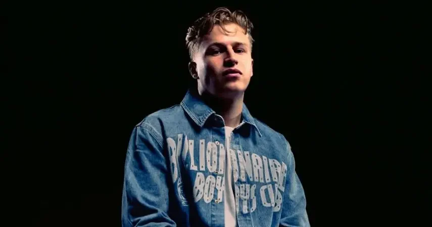 Tommy Phillips in a denim jacket posing against a black background.